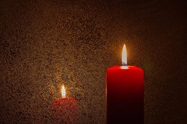 A burning candle on a dark orange reflective background — Stock Photo, Image
