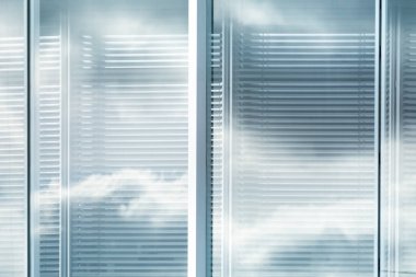 View of louvers window of modern office building with reflection of sky with clouds, blurred effect clipart