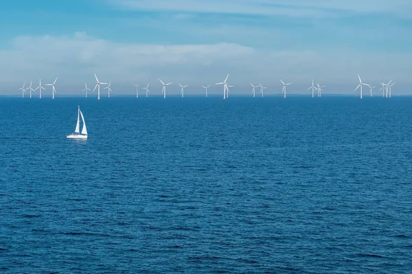 Alternatieve energie-rij van offshore windturbines en jacht op zee, groene energie Windmill generatoren op zee — Stockfoto