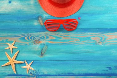 Yaşayan mercan renkli şapka üst görünümü, panjurlu güneş gözlüğü, ve mavi boyalı vintage ahşap doku denizyıldızı. Düz döşeme, kopyalama alanı.