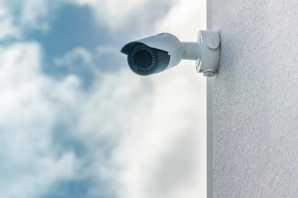 Cámara de seguridad CCTV en el fondo azul cielo delantero instalado en la pared blanca del edificio —  Fotos de Stock