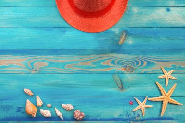 Mavi boyalı vintage ahşap doku üzerinde yaşayan mercan renkli şapka, deniz kabukları ve denizyıldızı üst görünümü. Düz döşeme, kopyalama alanı.