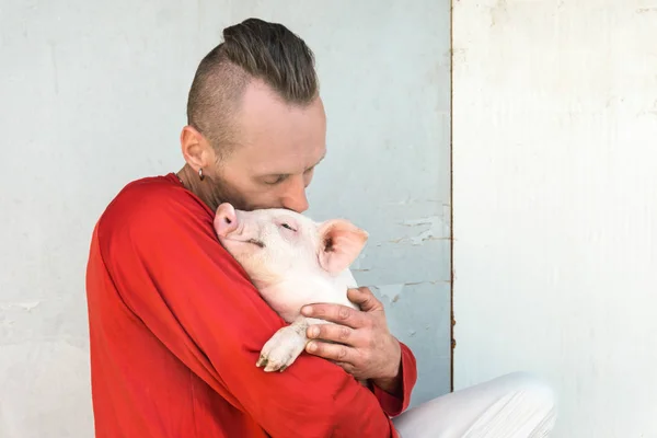 Çiftlik duvarında elinde sevimli Piglet ile domuz çiftçi. Piggy odaklanın.