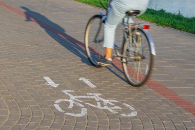 Bisiklet sürücüsü ve bisiklet işareti ile bisiklet yolunda gölge hareket bulanıklığı etkisi. Ekolojik ulaşım kavramı