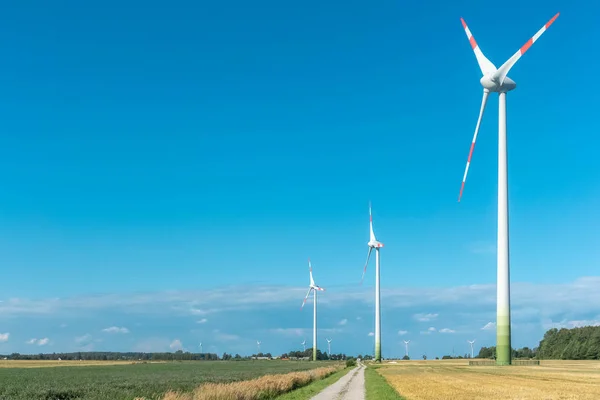 Wind turbines in agrarische velden op blauwe en bewolkte hemel achtergrond. Concept schone en hernieuwbare energie — Stockfoto