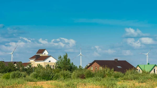 Wind turbines achter huizen in woonwijk op blauwe hemel achtergrond. Concept schone en hernieuwbare energie — Stockfoto