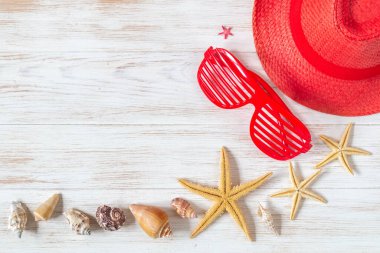Kırmızı renkli şapka, gözlükler, deniz yıldızları ve eski tahta üzerinde deniz kabukları. Bir sürü yaz aksesuarı. Şapka, gözlükler, deniz yıldızları. Fotokopi alanı olan deniz kabukları. Seyahat ve tatil konsepti..