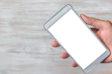Klasik ahşap arka planda elinde akıllı telefon cihazı var. Tahtada beyaz ekran olan el ele tutuşan telefon. Model için ahşap arka planda boş ekranlı cep telefonlu el