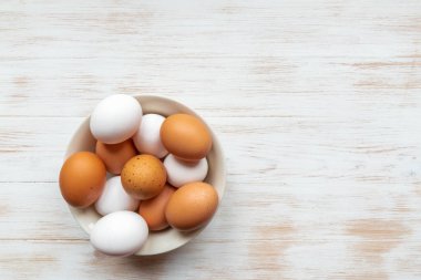 Kasede organik yumurta var. Ahşap arka planda beyaz ve kahverengi yumurtalar. Tahta masa üzerinde kahverengi ve beyaz tavuk yumurtası tabağı. Doğal sağlıklı besin konsepti. Üst görünüm, düz görünüm, kopyalama alanı