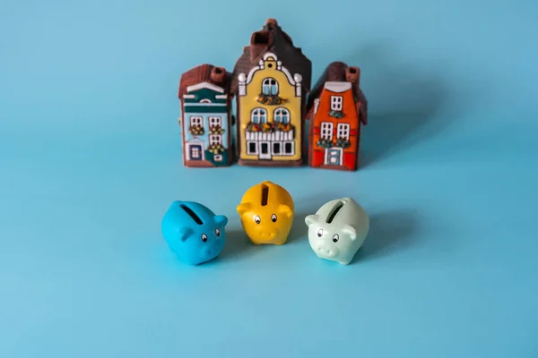 Piggy banks in front of real estate, house models. Savings for real estate project with small model houses and piggy banks. Concept of saving finances and real estate deposits.
