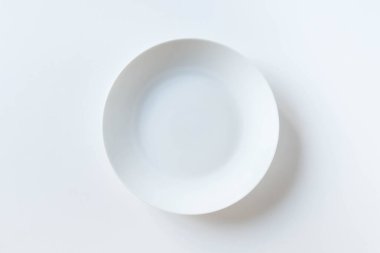 Beyaz arka planda izole edilmiş boş seramik yuvarlak tabak. Beyaz arka plana yerleştirilmiş beyaz plaka. Üst Manzara. Düz yatıyordu.