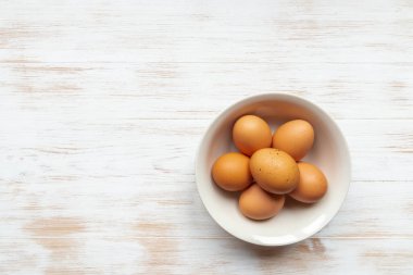 Tabaktaki organik yumurtaların en üst görüntüsü. Tabakta kahverengi tavuk yumurtası ve ahşap masa yatıyordu. Kahverengi yumurtalar ahşap arka planda fotokopi alanında. Doğal sağlıklı gıda konsepti.