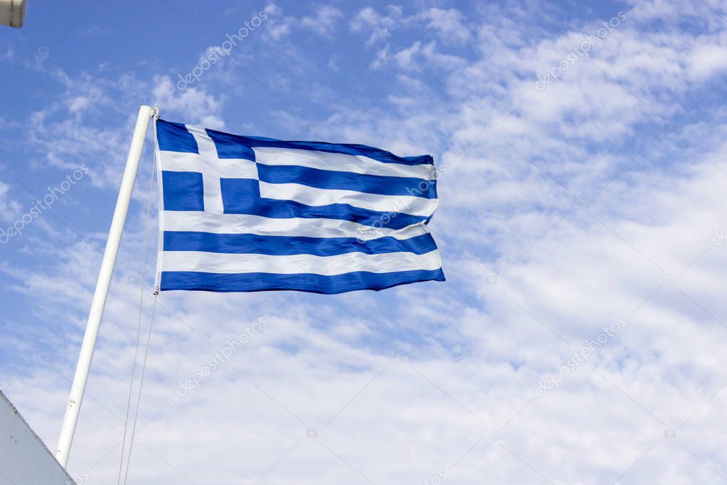 Front bottom shot of colorful waving greece flag with blue open sky background at Izmir in Turkey
