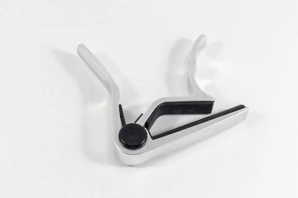 Clean top shoot of metal reflective guitar capo with white background