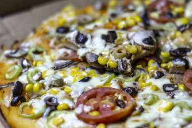 Dilimlerce domates, siyah zeytin, mısır ve biber ile ucuz ince pizza yakın çekim