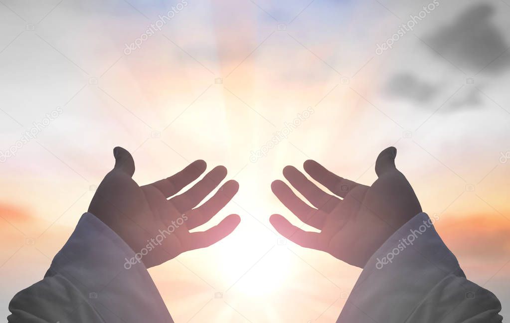 Ramadan kareem concept: Silhouette hands of God over blurred sunset background