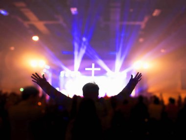 Church worship concept:Christians raising their hands in praise and worship at a night music concert clipart
