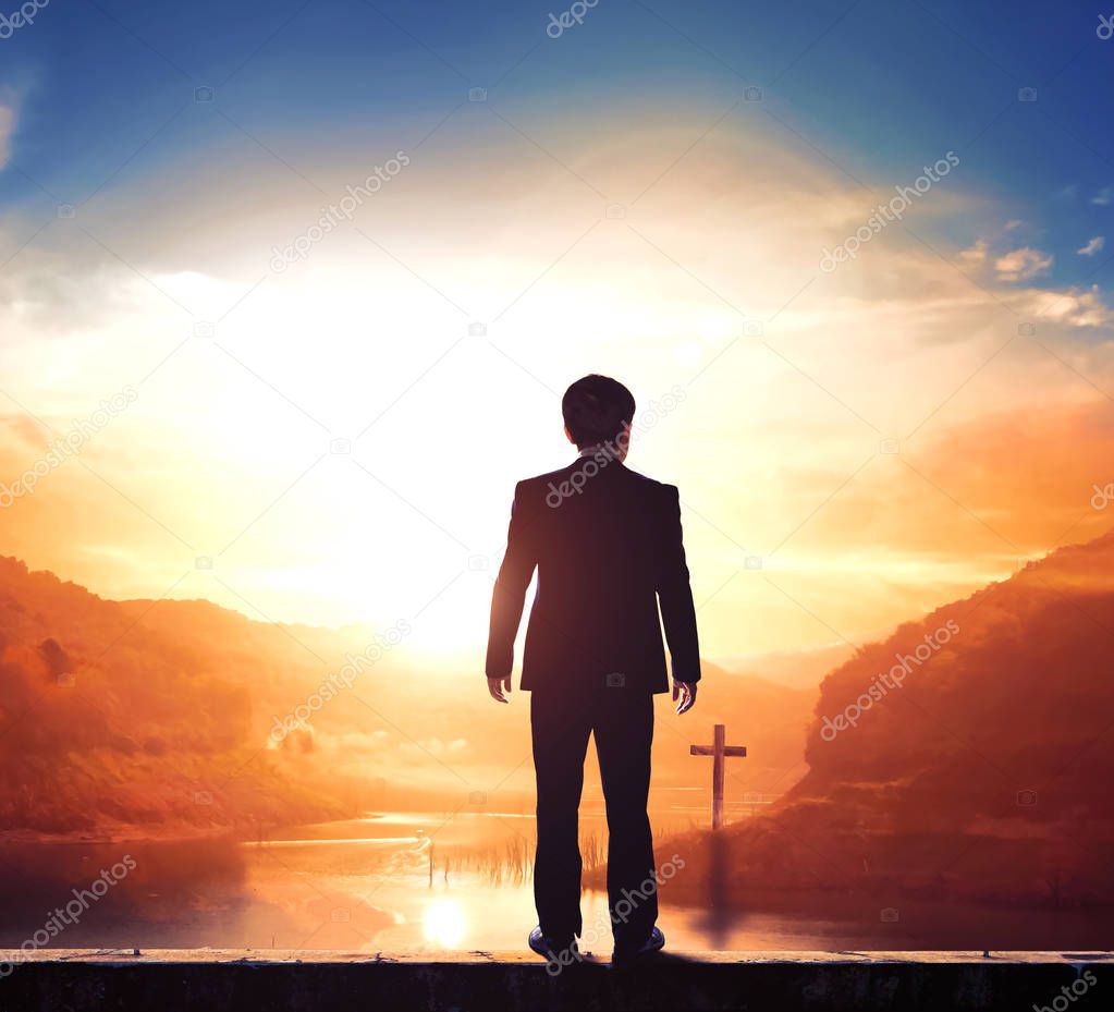 Business concept: businessman standing in front of the cross
