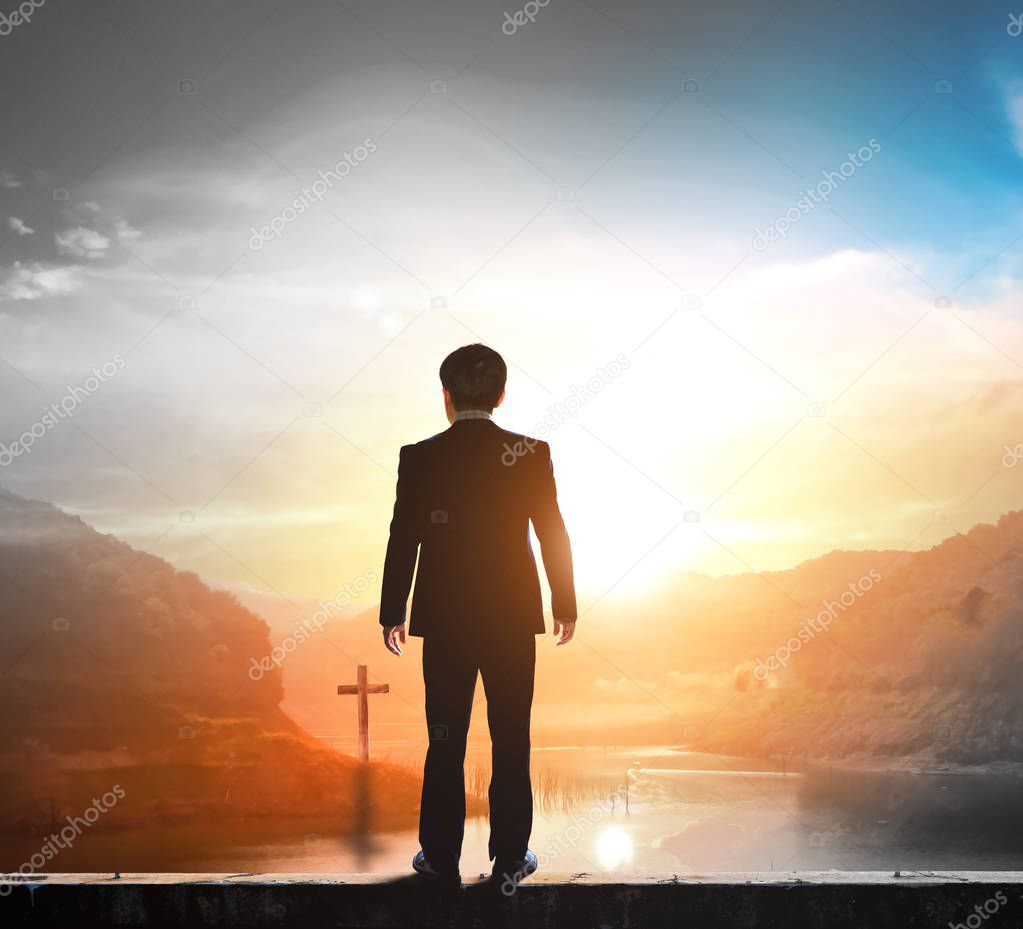 Business concept: businessman standing in front of the cross