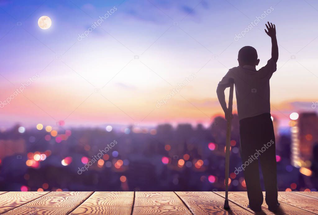 International Day of Persons with Disabilities concept? Silhouette a disabled man standing at mountain city background