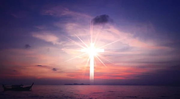 Concept of Jesus Christ: white cross on sunset sky background