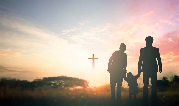 Family concept: Parents and children pray together on the cross background