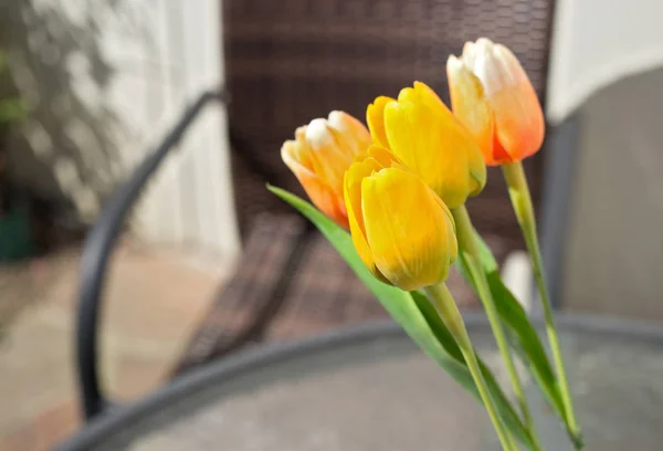 Bouquet of colorful tulips with garden chair in the background.
