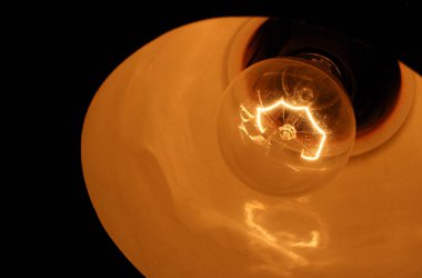 Ampul tha karanlıkta parlayan. Siyah arka plan üzerine izole göze batan ampul. Meditasyon.