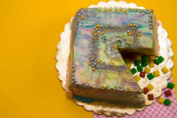 colored cut cake on a yellow background, decorated