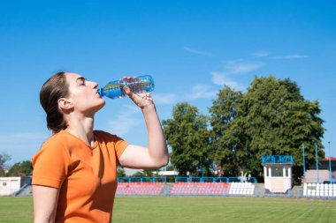 Kadın koşudan sonra su içiyor.