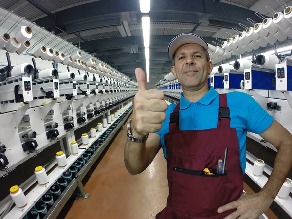 Industrial worker in textile factory during repair work showing thumbs up