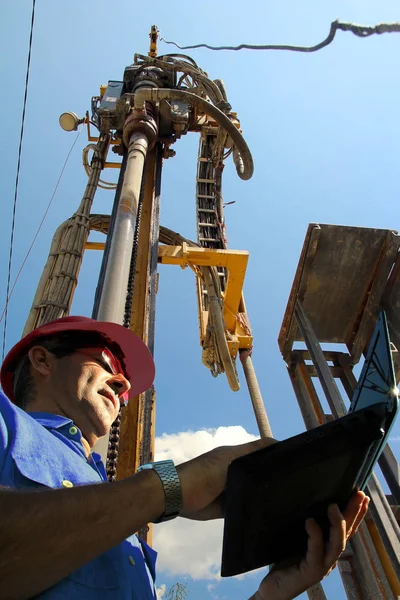 石油工程师与笔记本电脑在油田 — 图库照片