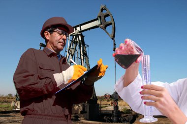 Kadın el dökülen ham petrol mühendisi blueprint ve bir petrol kuyusu ile önünde örneği arka planda