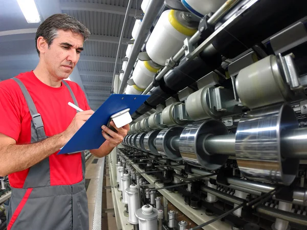 现代纺织厂使用剪贴板和书写的质量控制检查器 免版税图库图片