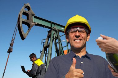 Başparmak gösterilmesini ve yeni bir petrol kaynağı açılması bir şişe şampanya ile kutluyor başarılı petrol mühendisi