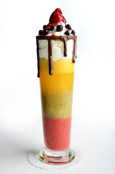 children\'s vitamin cocktail made from natural juices, decorated with caps of fresh air cream and poured with chocolate and strawberry topping.
