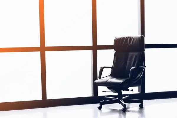 Black executive leather chair in empty office space with large window ,copy space.