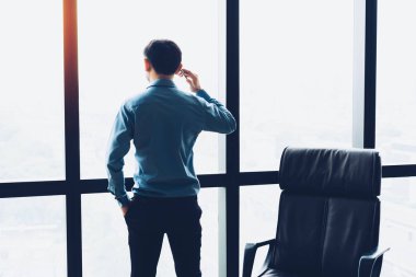 Büyük pencereler duran, cep telefonundan konuşuyor ve bakan mutlu işadamı