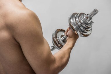 Güçlü adam gri arka plan üzerinde izole dumbbell ile çalışma dışarı