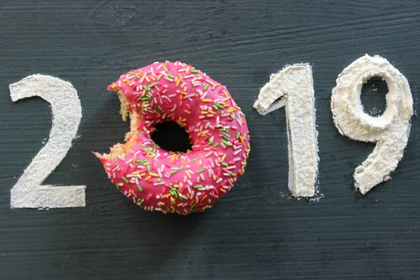 Siyah bir arka plan üzerinde rakamlar 2019 un, pembe çörek numarası 0, yeni yıl, tatlı hayat kavramı yerine dolu. Metin için boş alan
