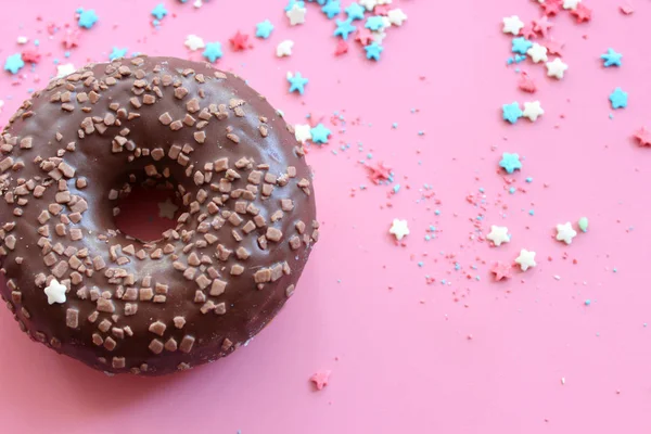 Chocolate-covered doughnut  on bright pink background close-up