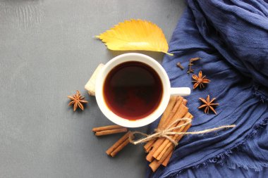 Sonbahar natürmort. Bir fincan sıcak çay sarı sonbahar yaprak ve baharatlar, tarçın, anason, karanfil bir eşarp mavi zemin üzerine yapışır. Sıcak ısınma içki, konfor, gevşeme, içki rahatlatıcı. Çay, baharat ve sonbahar dekor ahşap bir masa üzerinde kahve. Üstten görünüm,