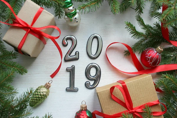 Yeni yıl 2019 olduğunu. Noel Noel ağaç dalları ve Noel dekorasyonları ahşap arka plan. Noel hediyeleri, çam dalları ve beyaz ahşap zemin üzerinde oyuncaklar.