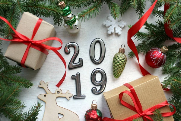 Yeni yıl 2019 olduğunu. Noel Noel ağaç dalları ve Noel dekorasyonları ahşap arka plan. Noel hediyeleri, çam dalları ve beyaz ahşap zemin üzerinde oyuncaklar.