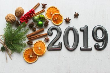 Noel kartı, çevrili Noel topları, çam dalları, tarçın, baharatlar, yakın çekim tarihi 2019 bir beyaz kağıt arka plan üzerinde kurutulmuş portakal, ahşap geyik. Kopya alanı.