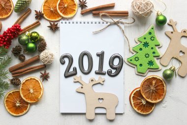 Noel kartı, çevrili Noel topları, çam dalları, tarçın, baharatlar, yakın çekim tarihi 2019 bir beyaz kağıt arka plan üzerinde kurutulmuş portakal, ahşap geyik. Kopya alanı.