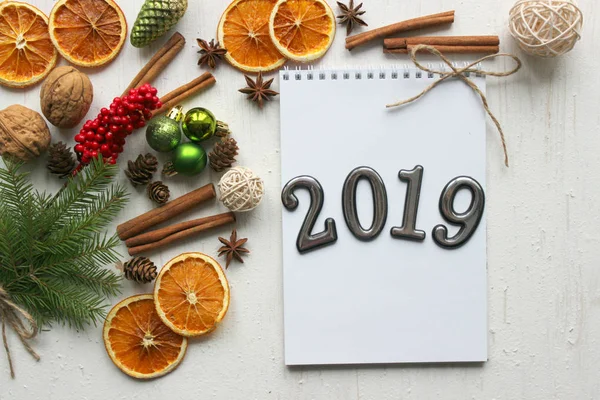 Noel kartı, çevrili Noel topları, çam dalları, tarçın, baharatlar, yakın çekim tarihi 2019 bir beyaz kağıt arka plan üzerinde kurutulmuş portakal, ahşap geyik. Kopya alanı.