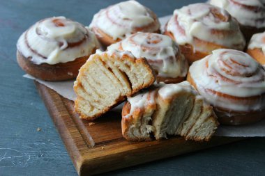 Güzel taze tarçın ruloları ahşap grunge doku masasına yakın çekim. Ev yapımı kekler, Cinnabon. Beyaz çay tabağında bir fincan çay, tarçın çubukları. Lezzetli Kahvaltı Büfesi.