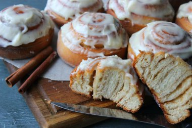 Güzel taze tarçın ruloları ahşap grunge doku masasına yakın çekim. Ev yapımı kekler, Cinnabon. Beyaz çay tabağında bir fincan çay, tarçın çubukları. Lezzetli Kahvaltı Büfesi.