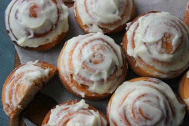 Güzel taze tarçın ruloları ahşap grunge doku masasına yakın çekim. Ev yapımı kekler, Cinnabon. Beyaz çay tabağında bir fincan çay, tarçın çubukları. Lezzetli Kahvaltı Büfesi.